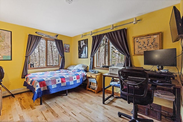 bedroom with wood-type flooring and a baseboard heating unit