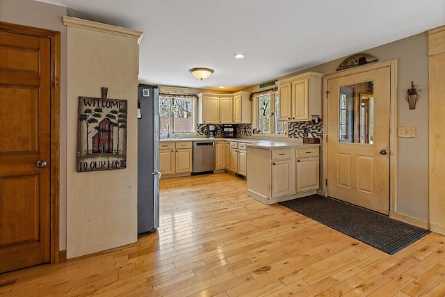 kitchen with light countertops, appliances with stainless steel finishes, a sink, and light wood finished floors