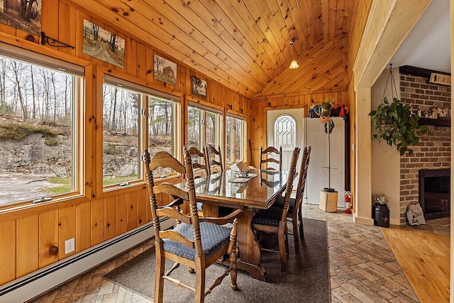 dining area with a brick fireplace, wood walls, wooden ceiling, vaulted ceiling, and a baseboard heating unit