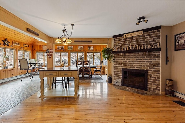 dining space with wood-type flooring, a brick fireplace, and a wealth of natural light