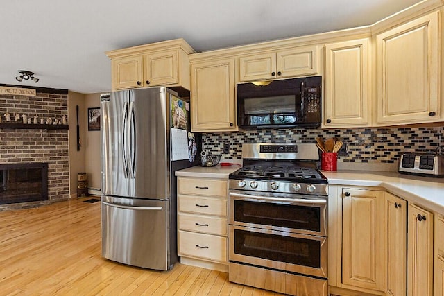 kitchen with light countertops, backsplash, light brown cabinetry, and appliances with stainless steel finishes