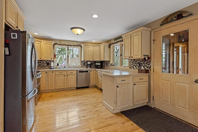 kitchen featuring a sink, light brown cabinets, light countertops, stainless steel appliances, and backsplash