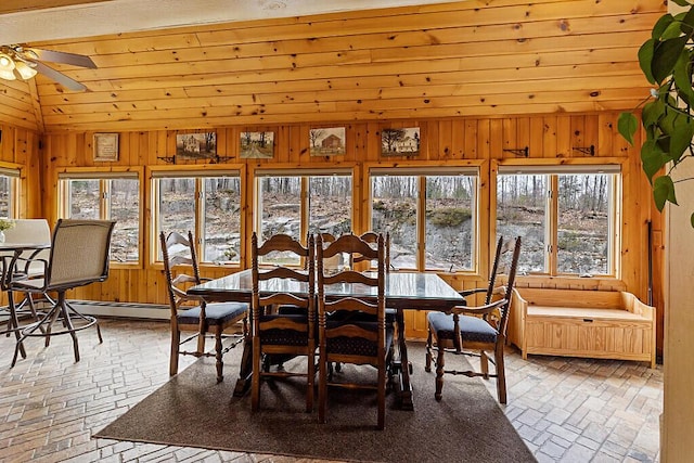 dining room featuring wooden walls, brick floor, vaulted ceiling, and ceiling fan