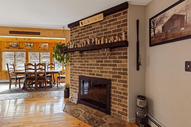 living room featuring wood-type flooring, a baseboard radiator, wood walls, and a fireplace