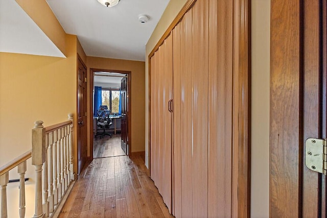 hall featuring light wood finished floors and an upstairs landing
