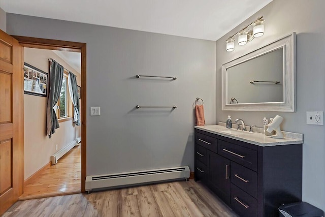 bathroom with vanity, a baseboard radiator, baseboards, and wood finished floors