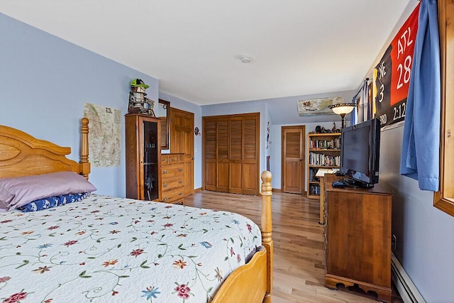 bedroom with light wood-style floors and a baseboard radiator