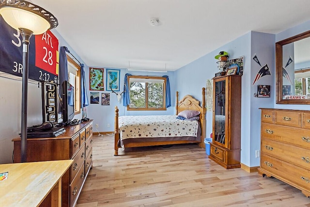 bedroom with baseboards, light wood-style flooring, and multiple windows