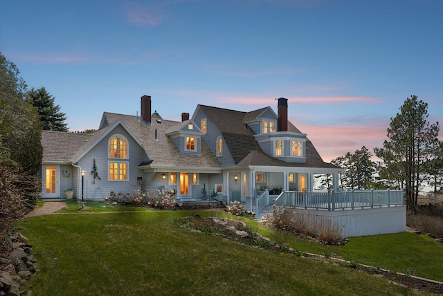 168 Ocean Ave, Kennebunkport, ME 04046 - back of house at dusk featuring roof with shingles, a chimney, a yard, and a porch