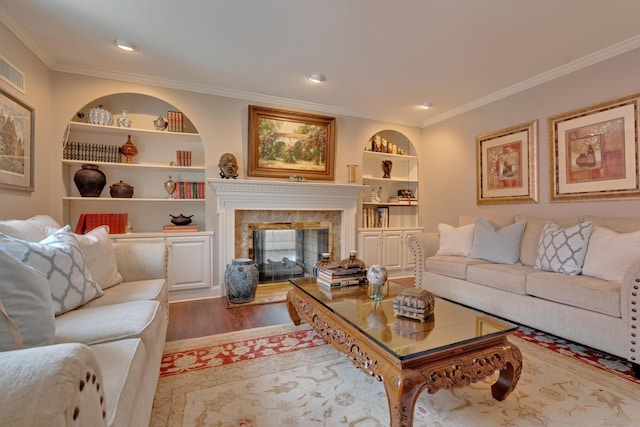 living area featuring crown molding, built in features, a high end fireplace, and wood finished floors
