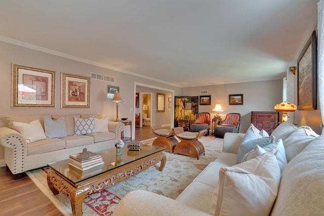 living area featuring baseboards, ornamental molding, wood finished floors, and visible vents