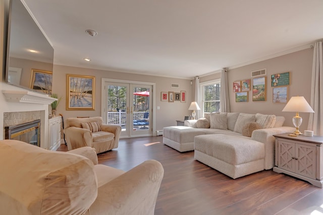 living area with visible vents, crown molding, a glass covered fireplace, dark wood-type flooring, and a baseboard radiator