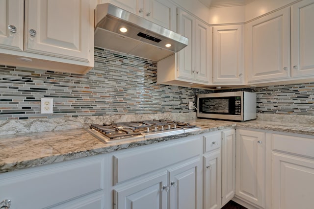 kitchen featuring ventilation hood, appliances with stainless steel finishes, backsplash, and white cabinetry