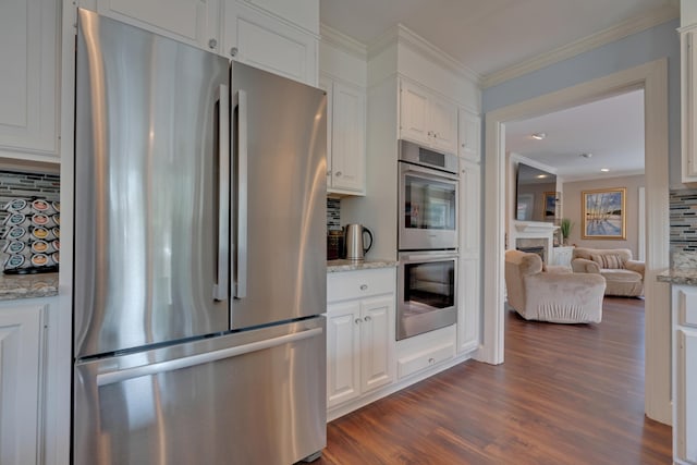 kitchen featuring backsplash, white cabinetry, appliances with stainless steel finishes, and dark wood finished floors