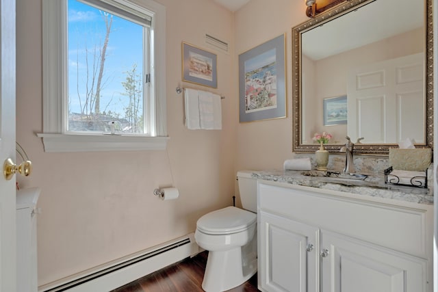 half bath with plenty of natural light, a baseboard heating unit, visible vents, and toilet