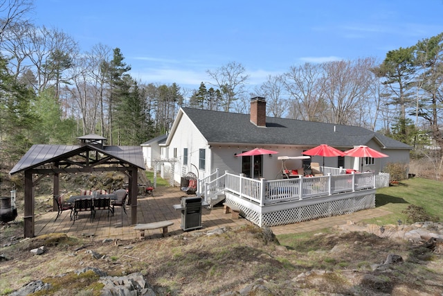 rear view of house featuring a wooden deck, a patio, roof with shingles, a chimney, and a gazebo