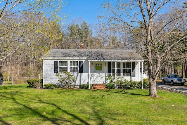 ranch-style home with a porch, a front lawn, and a chimney