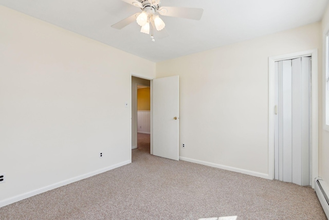 unfurnished bedroom featuring baseboard heating, baseboards, light carpet, and a closet