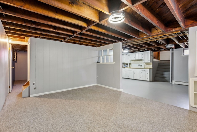 basement with a baseboard radiator, stairs, and a wealth of natural light