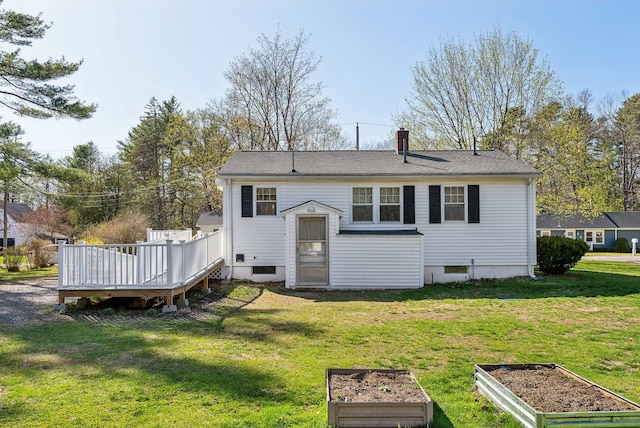 back of house with a lawn, a wooden deck, and a vegetable garden
