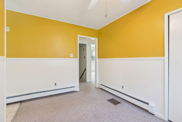 unfurnished room with a wainscoted wall, ornamental molding, baseboard heating, and visible vents