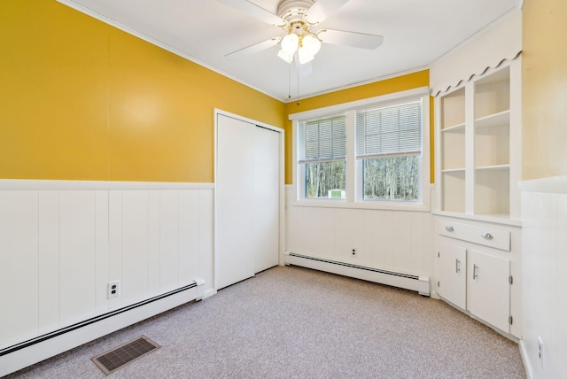 empty room featuring light carpet, a ceiling fan, a baseboard heating unit, and visible vents