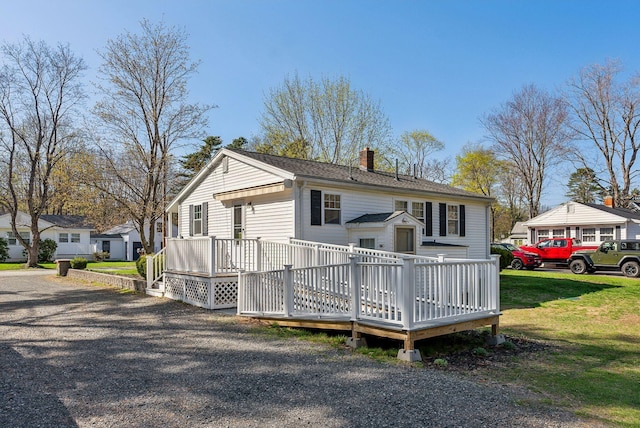 view of front of home with a chimney, a front lawn, and a deck