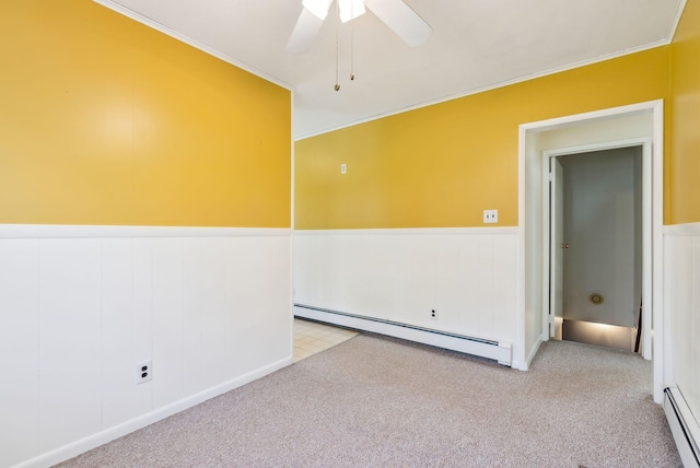 spare room featuring crown molding, wainscoting, carpet, and a baseboard radiator