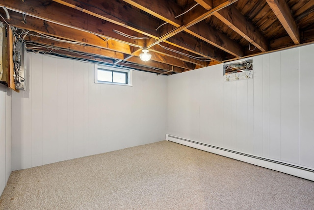below grade area with carpet floors, a baseboard heating unit, and wooden walls