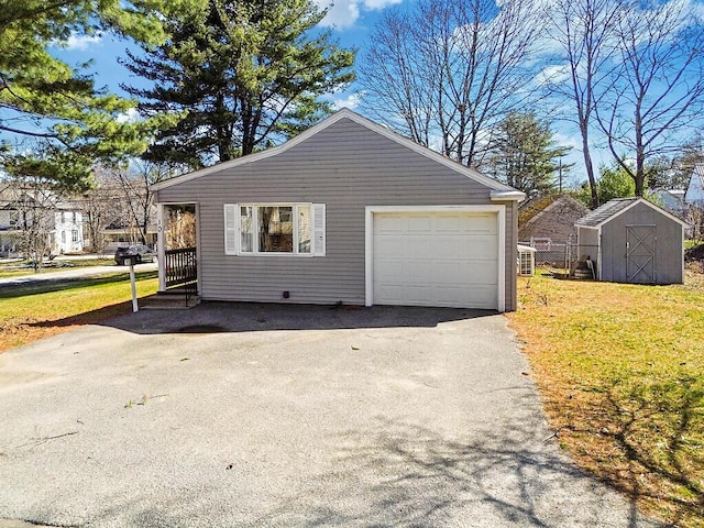 garage with driveway and a storage shed