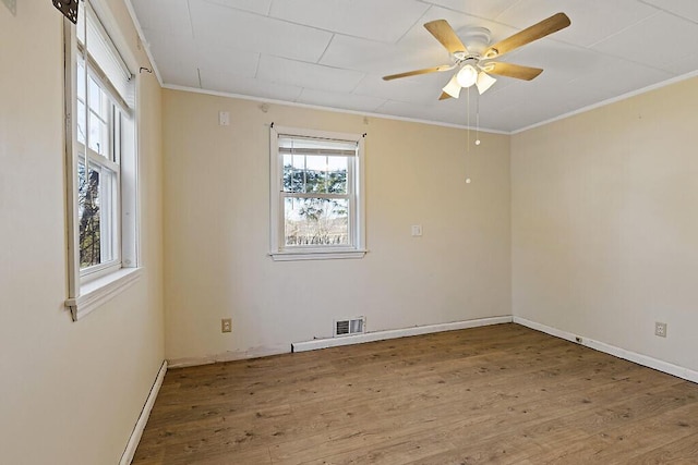 empty room featuring a ceiling fan, crown molding, and wood finished floors