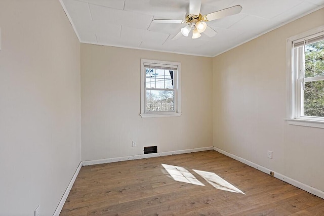 empty room featuring ceiling fan, ornamental molding, baseboards, and wood finished floors