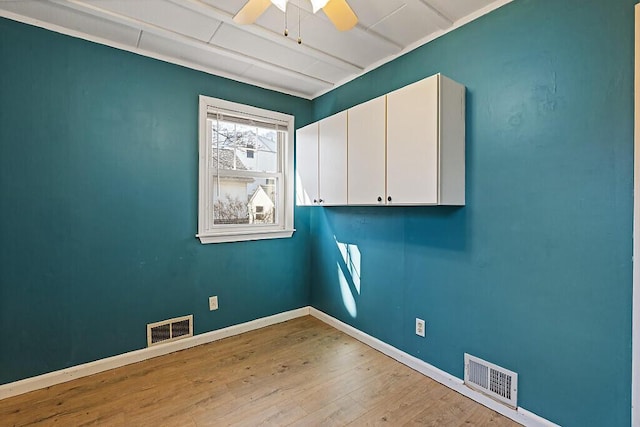 empty room featuring a ceiling fan, visible vents, wood finished floors, and baseboards