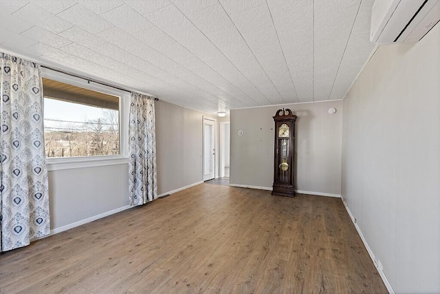 interior space with baseboards, a wall mounted AC, and hardwood / wood-style flooring