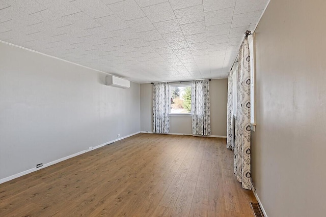 unfurnished living room featuring baseboards, hardwood / wood-style floors, and a wall mounted AC