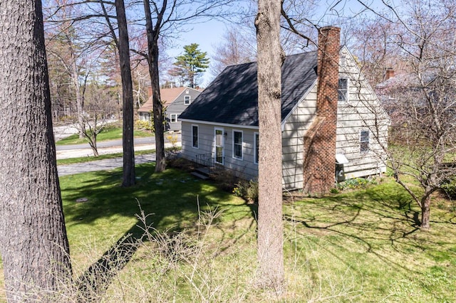 view of home's exterior featuring a lawn, a chimney, and a shingled roof