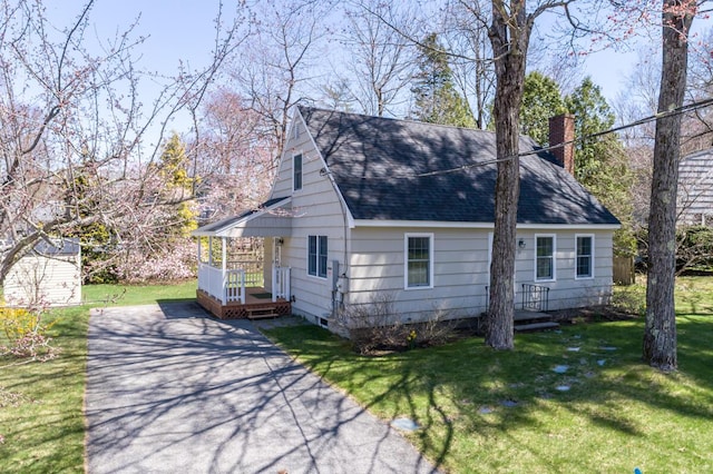 view of front of home with aphalt driveway, a chimney, a shingled roof, and a front lawn