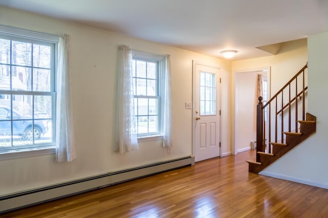 entryway with baseboards, wood finished floors, stairway, and a baseboard radiator