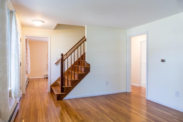 entryway with baseboards, a baseboard heating unit, stairs, and wood finished floors