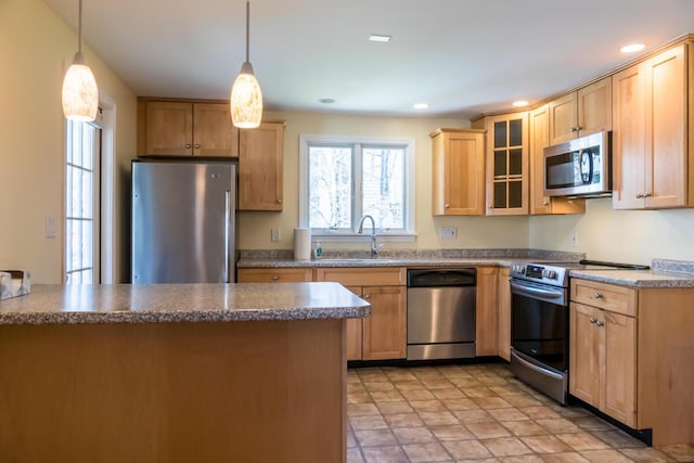 kitchen with decorative light fixtures, appliances with stainless steel finishes, a sink, a peninsula, and glass insert cabinets