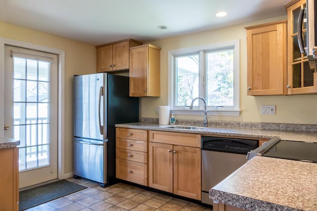 kitchen with a sink, light brown cabinets, stainless steel appliances, recessed lighting, and glass insert cabinets