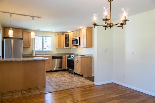 kitchen with wood finished floors, glass insert cabinets, baseboards, a notable chandelier, and stainless steel appliances