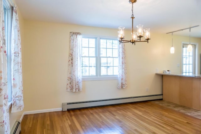 unfurnished dining area with baseboards, a baseboard radiator, wood finished floors, and a notable chandelier