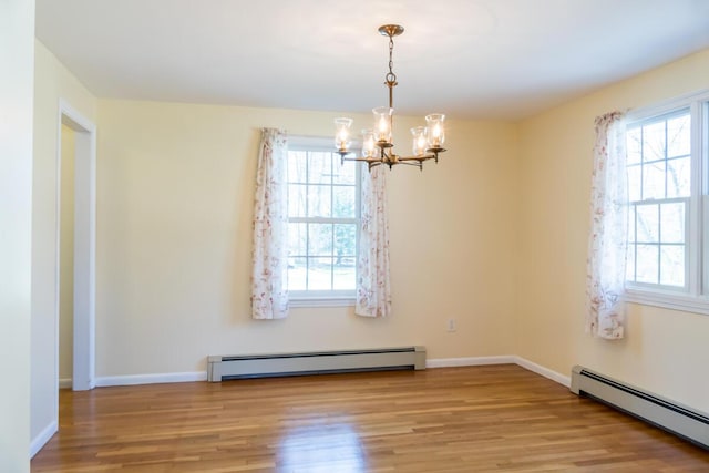 unfurnished dining area featuring an inviting chandelier, a baseboard heating unit, and wood finished floors