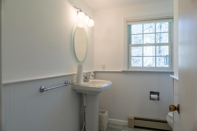bathroom featuring toilet, a baseboard heating unit, and a wainscoted wall