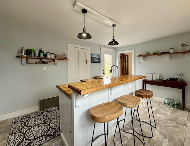 12 Prince Ave, Eastport, ME 04631 - kitchen featuring butcher block counters, baseboards, pendant lighting, and a kitchen breakfast bar