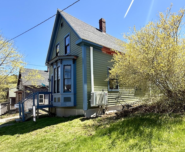 12 Prince Ave, Eastport, ME 04631 - view of side of home with a chimney, a lawn, cooling unit, and a shingled roof