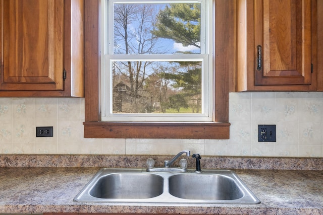 kitchen with a sink, decorative backsplash, and brown cabinets