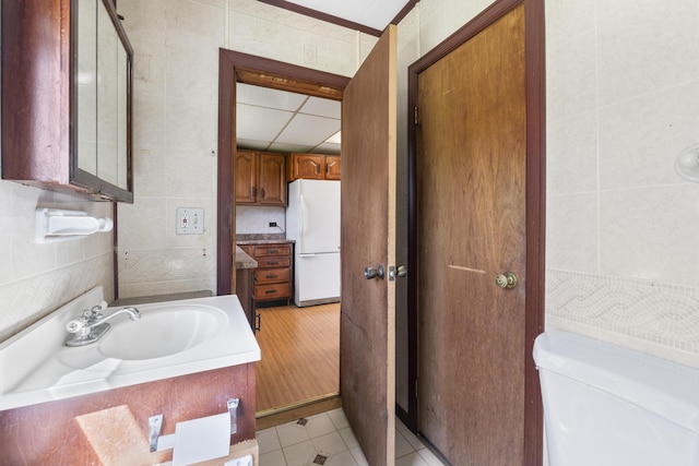 bathroom with tile patterned floors, vanity, toilet, and tile walls