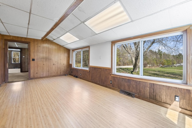 spare room with visible vents, wood finished floors, wooden walls, and vaulted ceiling